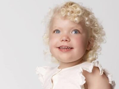 Beautiful young girl with SMS with blue eyes and blonde curly hair smiling