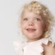 Beautiful young girl with SMS with blue eyes and blonde curly hair smiling